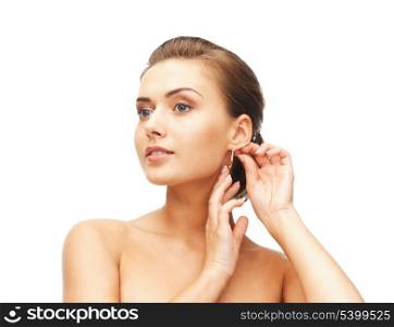 beauty and jewelry concept - beautiful woman trying on gold earrings
