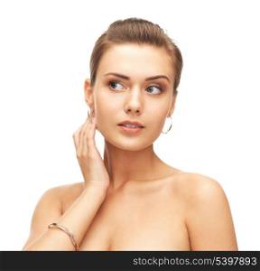 beauty and jewelry concept - beautiful woman wearing gold earrings and bracelet
