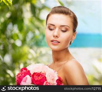 beauty and jewelry concept - woman wearing earrings and holding flowers