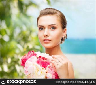 beauty and jewelry concept - woman wearing earrings, ring and holding flowers
