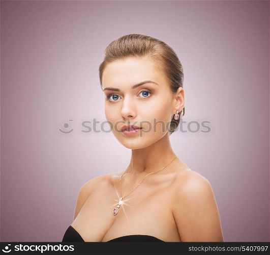 beauty and jewelry concept - woman wearing shiny diamond earrings and pendant