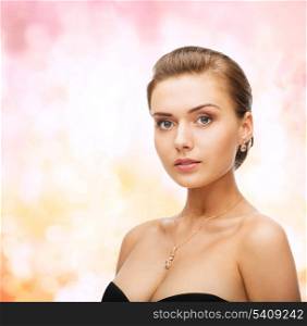beauty and jewelry concept - woman wearing shiny diamond earrings and pendant