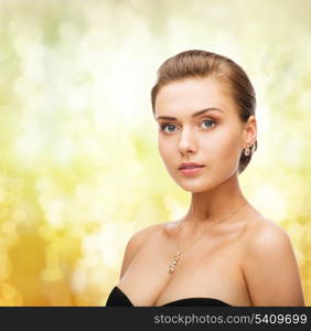 beauty and jewelry concept - woman wearing shiny diamond earrings and pendant