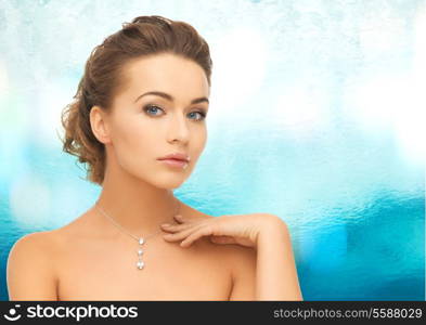 beauty and jewelry concept - woman wearing shiny diamond pendant