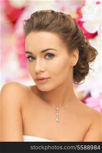 beauty and jewelry concept - woman wearing shiny diamond pendant