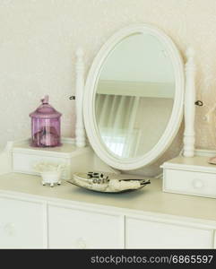 Beauty and make-up concept: mirror,jewelry and makeup set on a dressing table