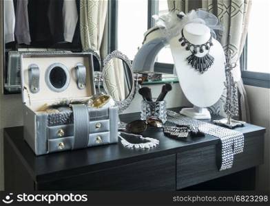 Beauty and make-up concept: table mirror,sunglasses,j ewelry and makeup brushes on a black table