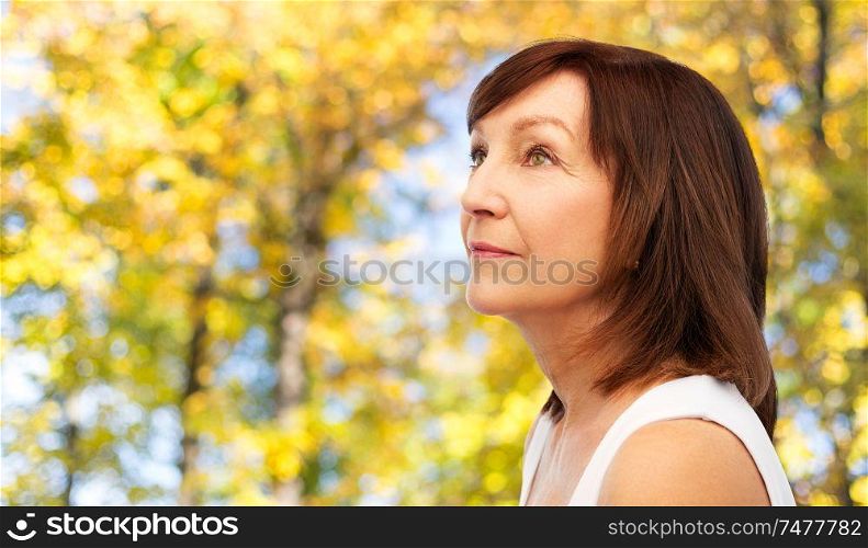 beauty and old people concept - portrait of senior woman over natural autumn background. portrait of senior woman in autumn