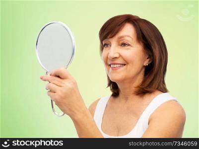 beauty and old people concept - portrait of smiling senior woman with mirror over lime green natural background. portrait of smiling senior woman with mirror
