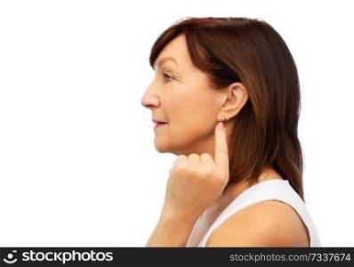 beauty and old people concept - profile of senior woman pointing to her golden earring over white. senior woman pointing to her golden earring