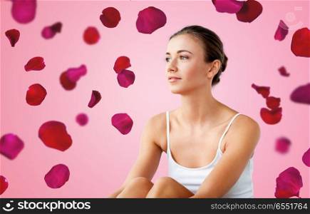 beauty and people concept - beautiful happy young woman over red rose petals on pink background. beautiful happy young woman over red rose petals. beautiful happy young woman over red rose petals