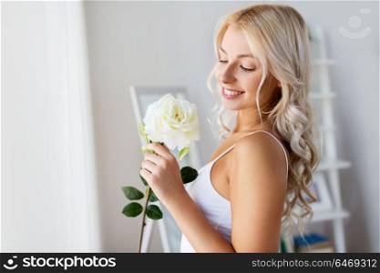 beauty and people concept - beautiful young woman in white underwear with rose flower in morning at home window. woman in underwear with rose flower at window