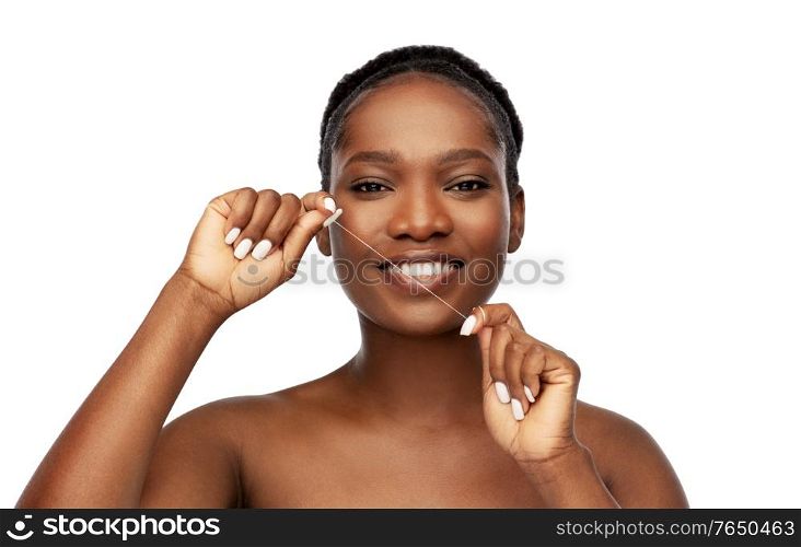 beauty and people concept - close up of of happy smiling young african american woman cleaning teeth with dental floss over white background. african woman cleaning teeth with dental floss