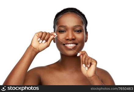 beauty and people concept - close up of of happy smiling young african american woman cleaning teeth with dental floss over white background. african woman cleaning teeth with dental floss