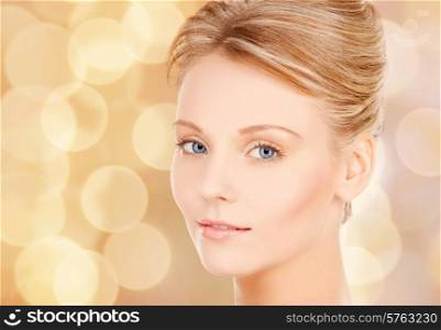 beauty and people concept - face of beautiful young woman over beige lights background