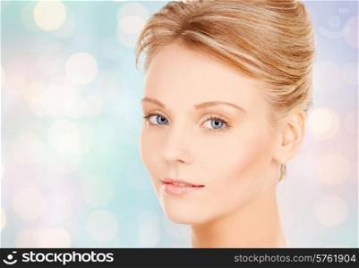 beauty and people concept - face of beautiful young woman over blue lights background