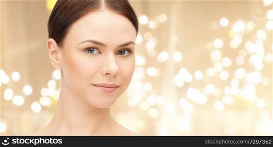 beauty and people concept - face of beautiful young woman over festive lights background. face of beautiful woman over lights background