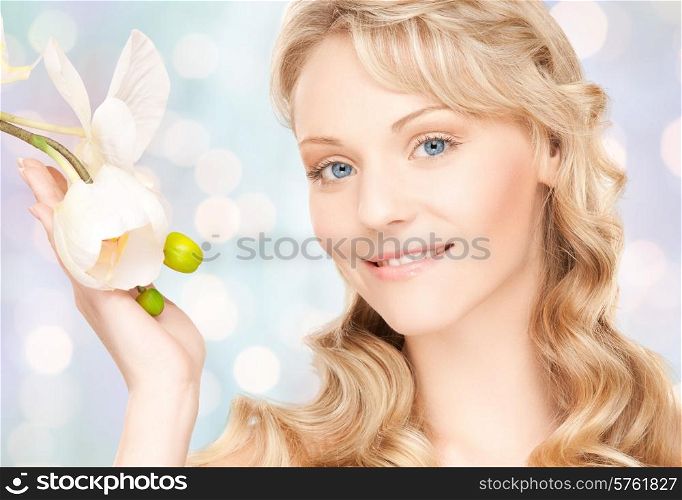 beauty and people concept - face of beautiful young woman with flower over blue lights background