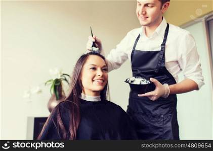 beauty and people concept - happy young woman with hairdresser coloring hair at salon. happy young woman coloring hair at salon
