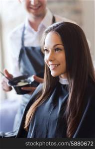 beauty and people concept - happy young woman with hairdresser coloring hair at salon. happy young woman coloring hair at salon
