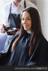 beauty and people concept - happy young woman with hairdresser coloring hair at salon