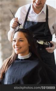 beauty and people concept - happy young woman with hairdresser coloring hair at salon. happy woman with stylist coloring hair at salon