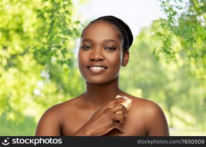 beauty and people concept - portrait of happy smiling young african american woman with bare shoulders over green natural background. portrait of young african american woman