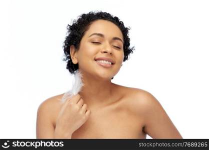 beauty and people concept - portrait of happy smiling young african american woman with bare shoulders and feather over white background. happy african american woman with feather