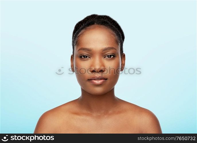 beauty and people concept - portrait of young african american woman with bare shoulders over blue background. portrait of young african american woman