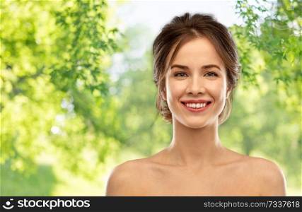 beauty and people concept - smiling young woman with bare shoulders over green natural background. smiling young woman over grey background