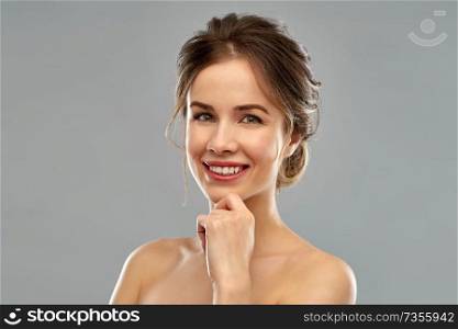 beauty and people concept - smiling young woman with bare shoulders over grey background. smiling young woman over grey background