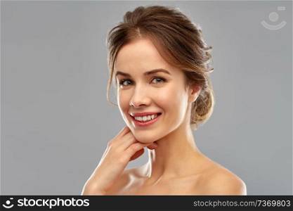 beauty and people concept - smiling young woman with bare shoulders over grey background. smiling young woman over grey background