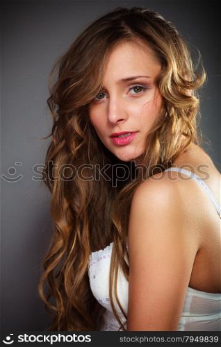Beauty and sensuality of women. Young attractive long haired girl wearing lingerie on gray background.