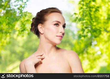 beauty and skin care concept - beautiful young woman touching her neck over green natural background. beautiful young woman touching her neck. beautiful young woman touching her neck