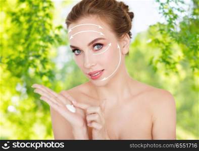 beauty and skin care concept - happy young woman with moisturizing cream on hand over green natural background. happy young woman with moisturizing cream on hand. happy young woman with moisturizing cream on hand