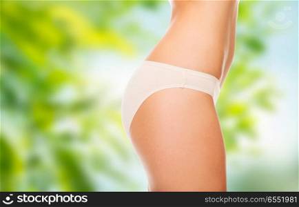 beauty and slimming concept - close up of woman body in cotton underwear over green natural background. close up of woman body in cotton underwear. close up of woman body in cotton underwear