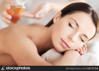 beauty and spa concept - beautiful woman in spa salon getting oil treatment