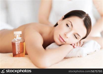beauty and spa concept - beautiful woman in spa salon getting oil treatment