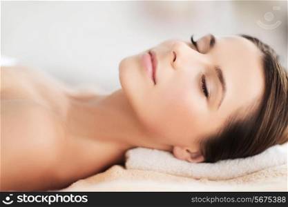 beauty and spa concept - beautiful woman in spa salon lying on the massage desk