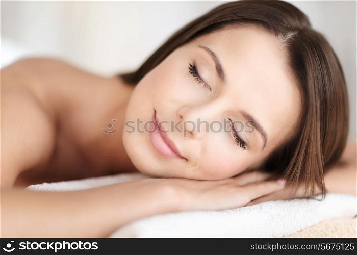 beauty and spa concept - beautiful woman with closed eyes in spa salon lying on the massage desk