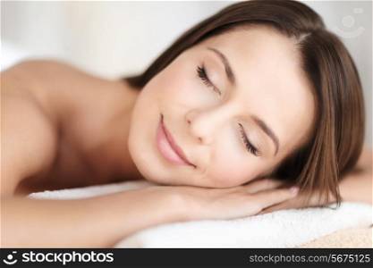 beauty and spa concept - beautiful woman with closed eyes in spa salon lying on the massage desk