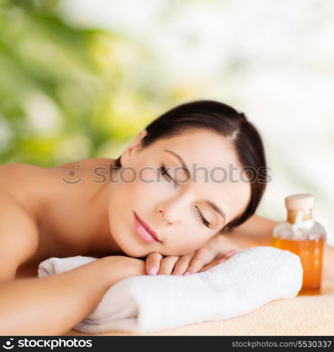 beauty and spa concept - happy woman in spa salon lying on the massage desk