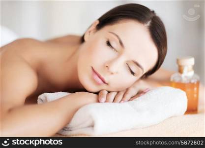 beauty and spa concept - happy woman in spa salon lying on the massage desk