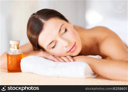beauty and spa concept - happy woman in spa salon lying on the massage desk. happy woman in spa salon