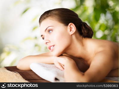 beauty and spa concept - woman in spa lying on the massage desk