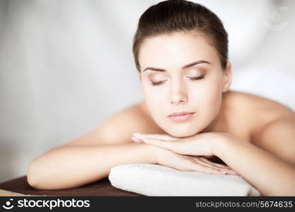 beauty and spa concept - woman in spa salon lying on the massage desk