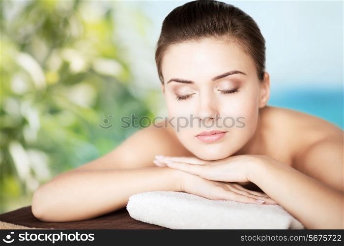 beauty and spa concept - woman in spa salon lying on the massage desk