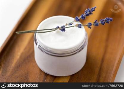 beauty and wellness concept - close up of lavender moisturizer on wooden tray. close up of lavender moisturizer on wooden tray