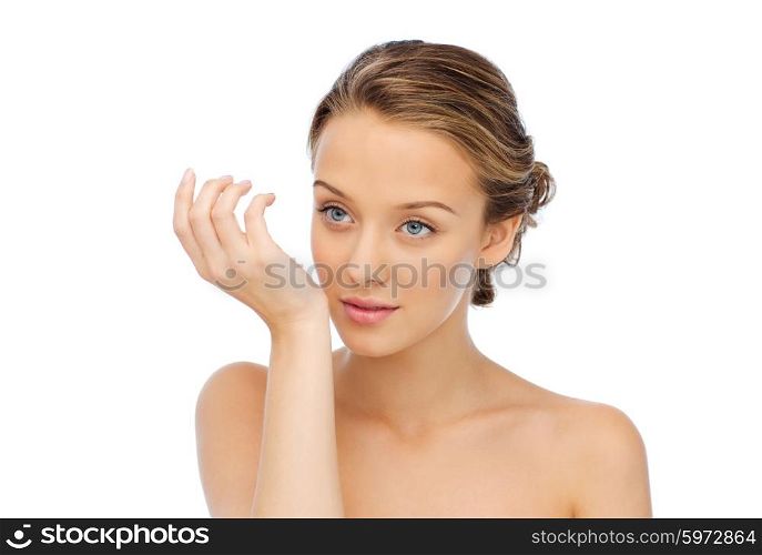 beauty, aroma, people and body care concept - young woman smelling perfume from wrist of her hand