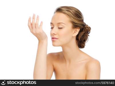 beauty, aroma, people and body care concept - young woman smelling perfume from wrist of her hand